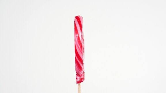 红色彩色螺旋棒棒糖视频旋转糖果棒上的焦糖在旋转糖果的主题圆形扭曲的糖果在心形塑造在一个白色的背景