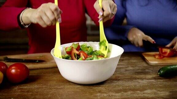 一个女人在搅拌一碗新鲜蔬菜沙拉