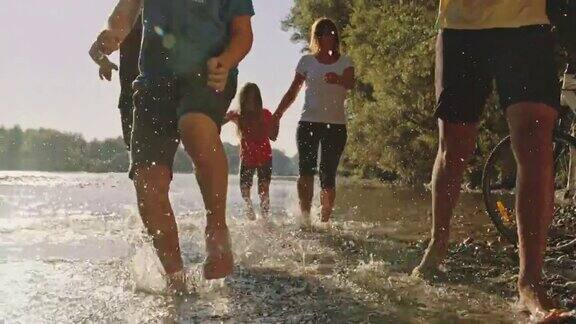 一个带着三个孩子的家庭在河的浅水中奔跑