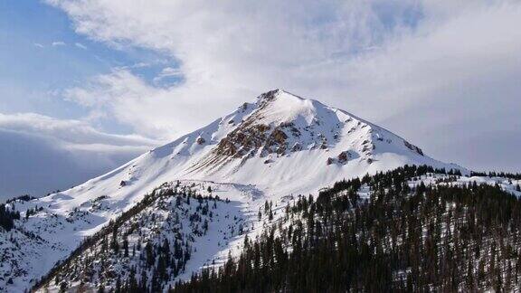无人机拍摄的积雪覆盖的山脉在科罗拉多州的落基山脉下部分多云但晴朗的冬季天空