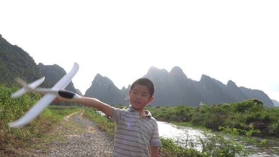 亚洲男孩在户外玩飞机模型
