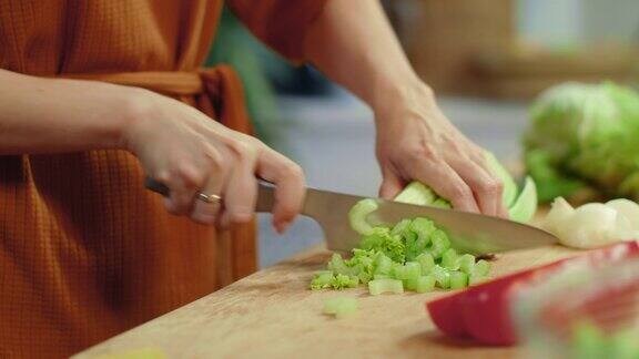 女人用手在菜板上切芹菜家庭主妇烹饪新鲜蔬菜