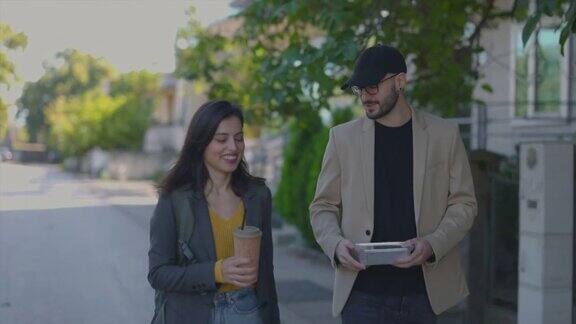 微笑的情侣走在人行道上他们带着外卖和咖啡