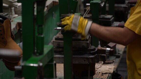 男工人粘合鞋底与一个压在鞋厂