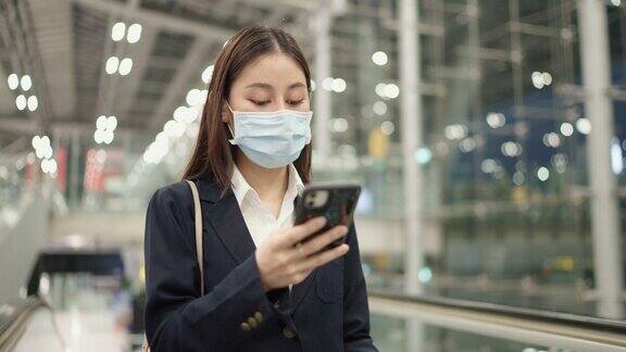 女投资者戴着医用口罩在机场用智能手机检查登机牌