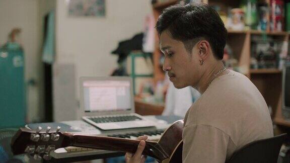 亚洲男子在家学习弹吉他的库存视频