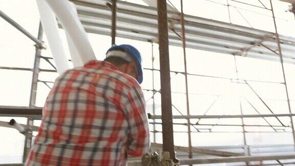 在建筑工地管道工人正从脚手架楼梯上搬运波纹塑料管