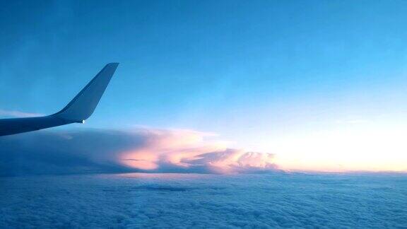 一架飞机的机翼从一个窗口飞过在日落时飞机的云层