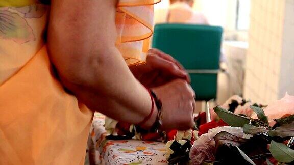 女人的手正在用玫瑰花瓣为印度传统节日制作项链用花瓣和玫瑰花蕾串成项链这是印度文化
