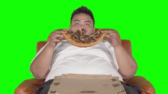一个胖子正在吃一大块披萨