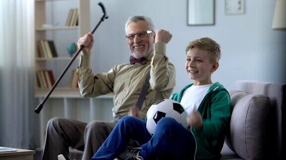 爷爷和孙子为最喜欢的足球队加油为胜利而高兴