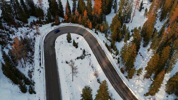 空中无人机拍摄的汽车行驶通过蜿蜒的道路沿着雪山白云石阿尔卑斯森林