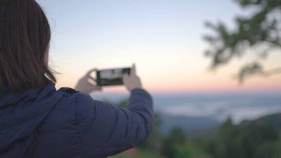 女旅行者在山区自然国家公园用智能手机拍风景照片