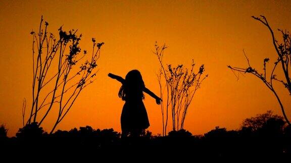 一个小女孩欣赏着落日的剪影