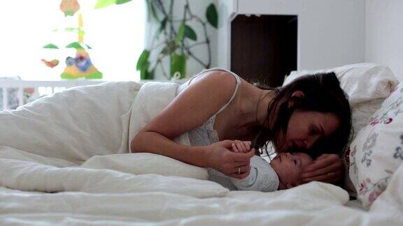 年轻的母亲抱着她刚出生的儿子在床上爱抚着他