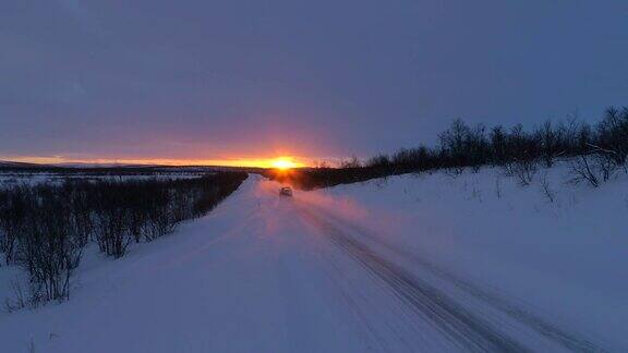 镜头:在冬日金色的夕阳下高速汽车行驶在白雪覆盖的森林道路上