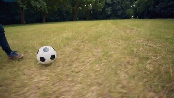 在室外踢足球的孩子那个男孩在公园里踢足球把脚放在球上