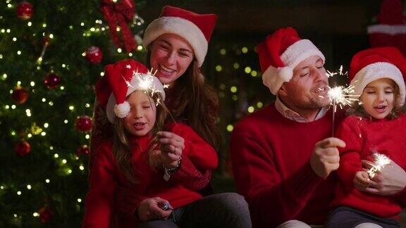 欢乐的一家人戴着圣诞帽手里拿着烟花唱着圣诞歌的慢镜头
