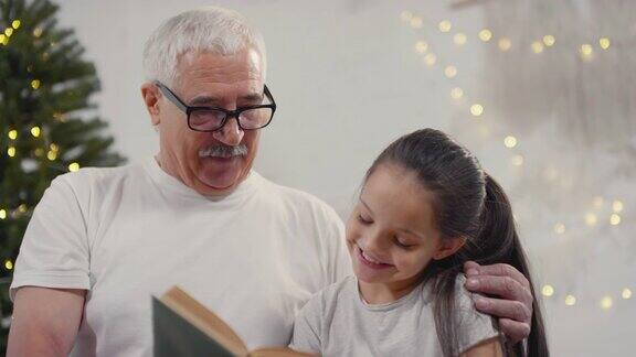 爷爷奶奶和可爱的女孩一起在圣诞节看书