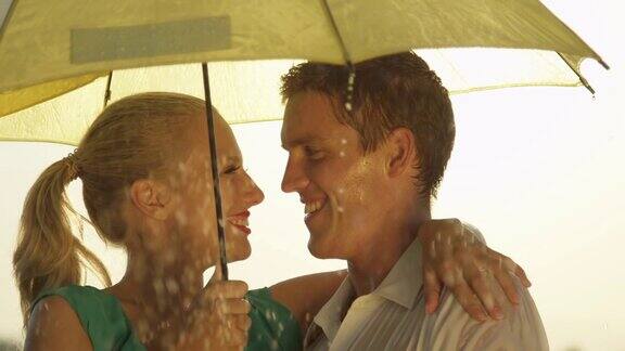 雨中一对年轻夫妇在伞下旋转