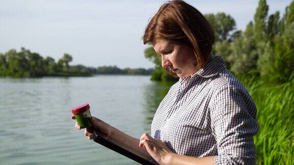 女研究员拿着药片检查带有绿藻的河水样本