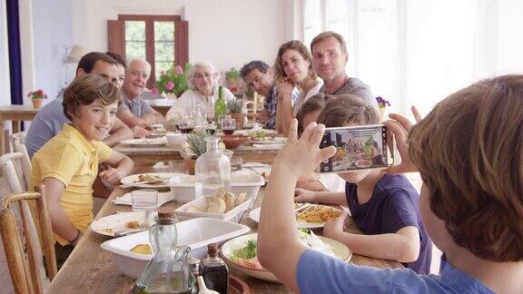男孩在餐桌上通过电话拍摄家人