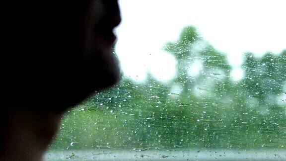 特写侧面的司机的侧面的一个人水滴在汽车的侧窗而驾驶这个PIC显示司机他在雨天驾驶他的车