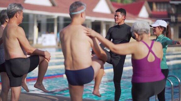 亚洲华人高中生游泳课前在泳池边与游泳教练做热身运动