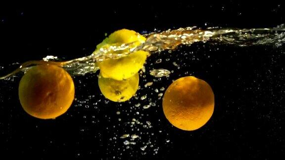 黄色的柠檬橙色水果落入水中黑色背景慢动作