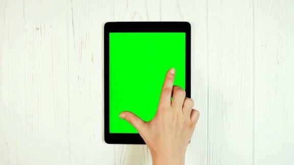 一个手指在平板电脑的绿色屏幕上滑动缩小的手势