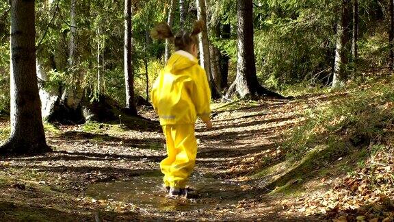 穿着黄色橡皮服的小女孩正在水坑里跳慢动作
