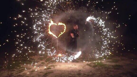 火表演男子艺术家扭曲手中的火物体以燃烧的心为背景