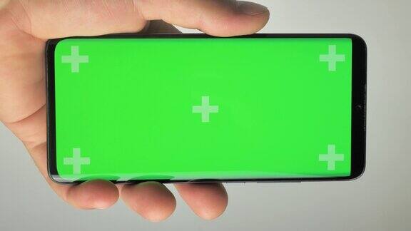 垂直视频一个男人拿着一个绿色屏幕的手机