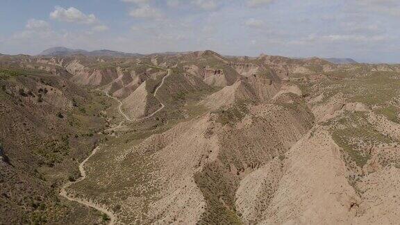 鸟瞰图的干燥山谷和山脉在GorafeDesiertodelosColoraos在蓝天内华达山脉格拉纳达西班牙在安达卢西亚有植被的西班牙沙漠峡谷无人机缓慢移动4K