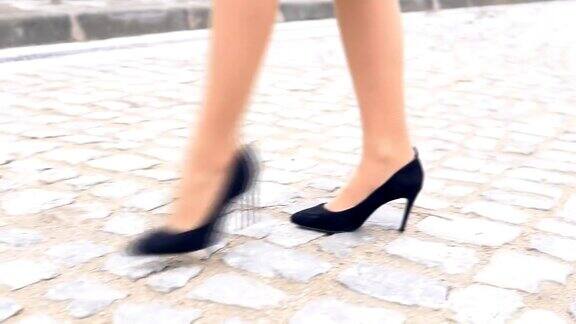 穿着黑鞋的女人的腿在石头路上