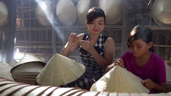 两名同胞越南工匠在老传统房子制作传统越南帽子的4k镜头低光场景在ApThoiPhuoc村Cantho省越南传统艺术家