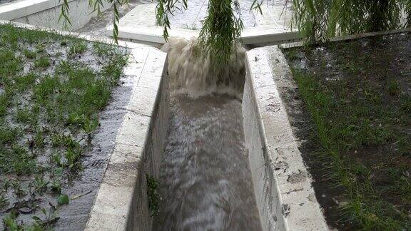 特写镜头显示在大雨期间一股湍急的脏水通过暴雨下水道的石头排水沟流入河中坏天气概念4k