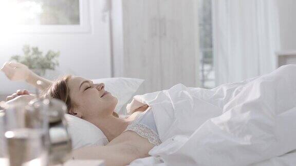 一个女人躺在床上伸懒腰睡觉