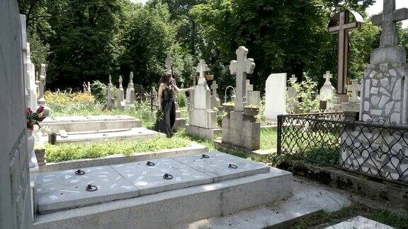 葬礼哥特式女孩走在古老墓地的墓碑旁思考死亡和孤独