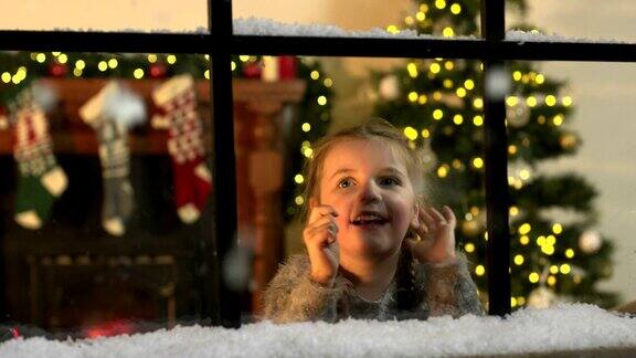 孩子看着雪花从窗户飘落在圣诞节