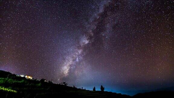 夜空中稻田上小屋上空银河的时间流逝