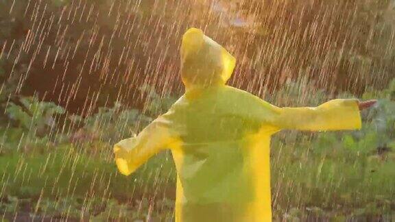 快乐可爱的小男孩微笑着举起双手穿着黄色雨衣享受着快乐的雨孩子在阳光下玩雨滴快乐家庭夏天秋天童年梦想概念4K