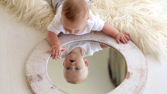 一个可爱的新生婴儿躺在家里的床上玩着镜子