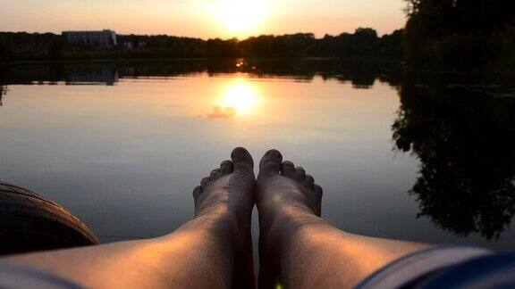 脚躺在湖边池塘附近的码头上
