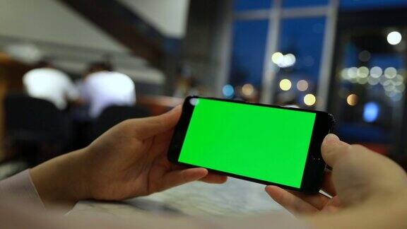 在咖啡馆拿着绿色屏幕的手机