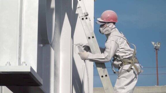 穿防护服的工人用白色油漆油漆建筑结构