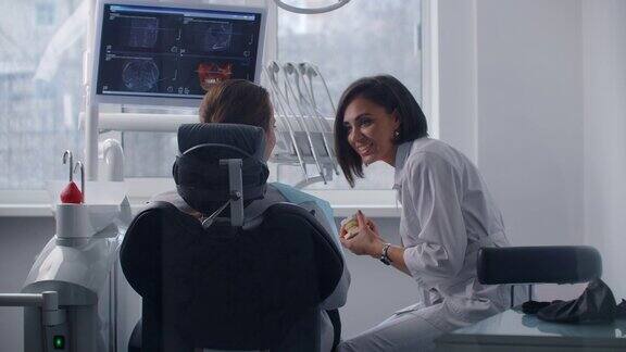 正畸医生与病人交流向他展示牙齿模型和核磁共振成像