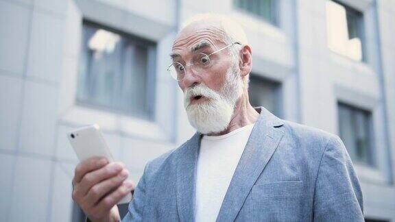 兴奋的老人正在用智能手机阅读电子邮件惊喜的好消息
