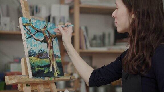 在艺术工作室里一个女人正在用颜料在图画上画细节