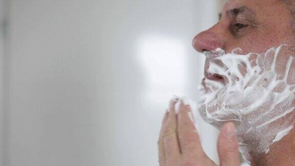 成熟英俊的男人在镜子前刮胡子